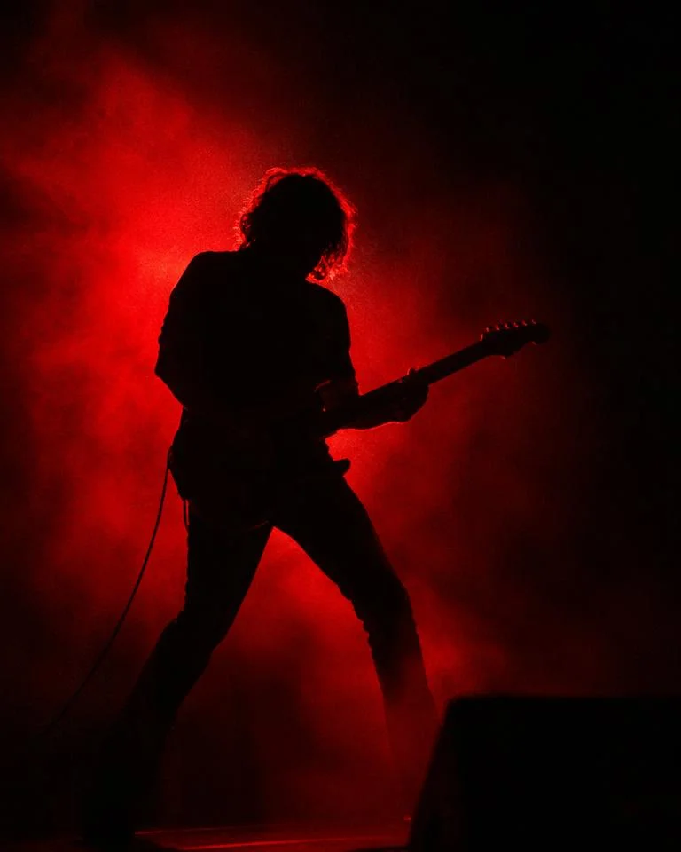 Red-backlit silhouette of a guitarist on stage
