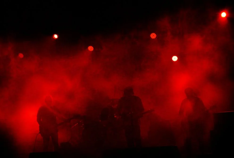 Club stage in red haze with band silhouettes