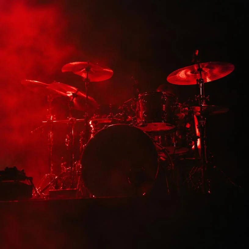 Red-lit drum kit in stage haze