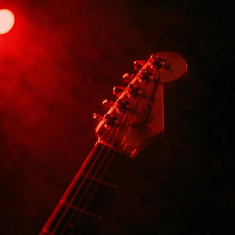 Guitar headstock under a red spotlight
