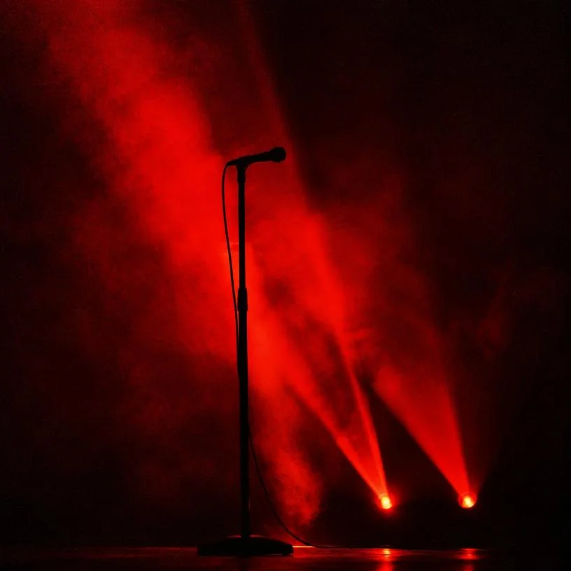 Microphone stand silhouette against red light beams